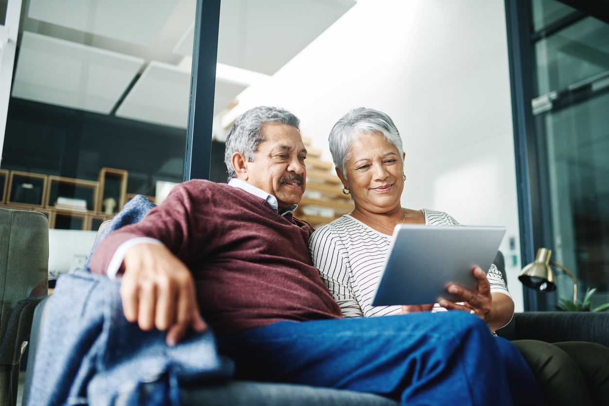 Shot of a mature couple using a digital tablet while relaxing at home