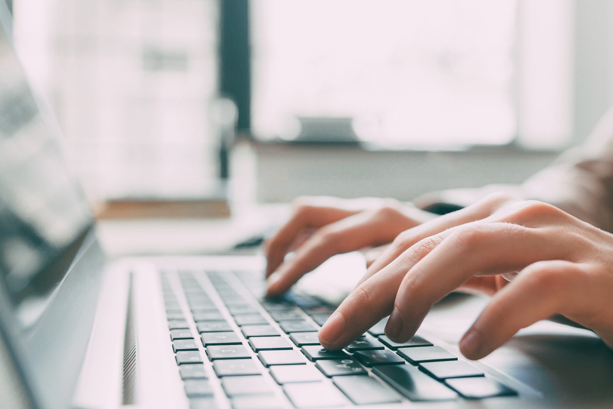 Hands typing on a laptop